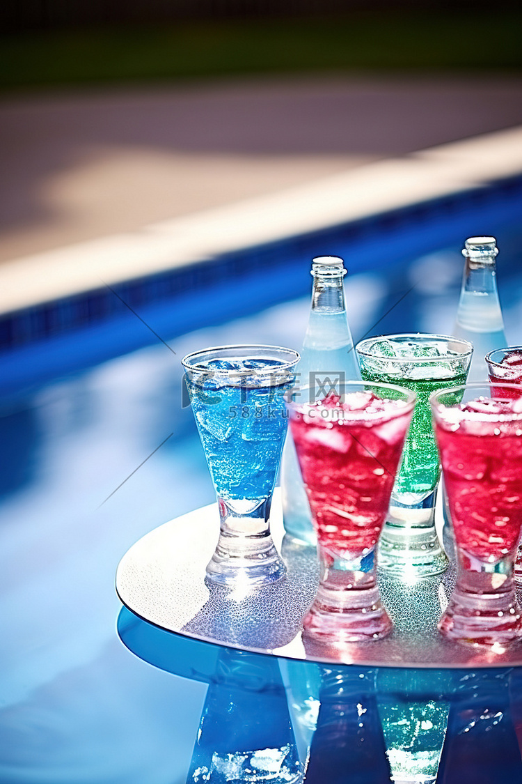 泳池边的蓝绿色粉色和紫色饮料杯