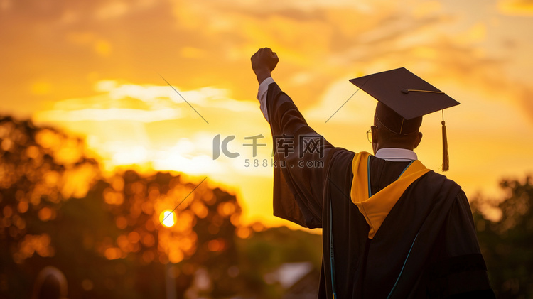 夕阳下举起拳头的毕业生背影图片