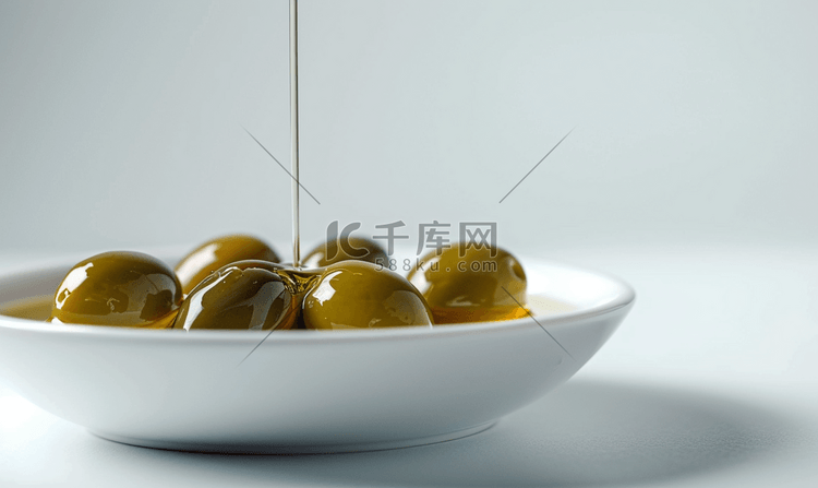细细的橄榄油流在碗里的橄榄上
