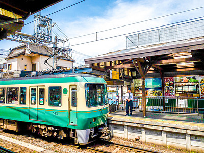 日本火车站的绿色小火车和铁轨摄影图