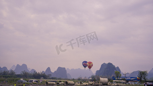 热气球飘带摄影照片_山间起飞热气球摄影图