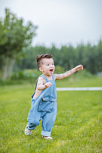 八月你好摄影照片_草地上奔跑的小男孩