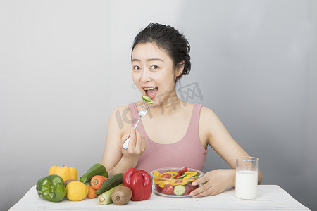 水果女孩摄影照片_用叉子吃黄瓜的女孩