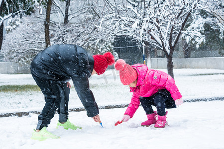 冬天立冬下雪雪花摄影照片_雪地里玩耍的小孩子