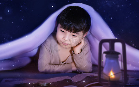 书小孩摄影照片_夜晚在被窝里看书的小男孩
