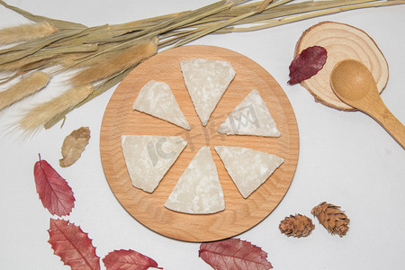 椰子糖切片木制摆盘树叶装饰纯色实物特写美食摄影图