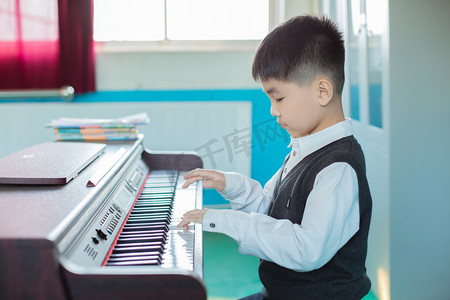 钢琴演奏节目单摄影照片_在练琴房弹琴的孩子