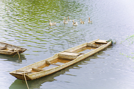 木质纹摄影照片_水面上漂泊的船只和游远的鸭群摄影图