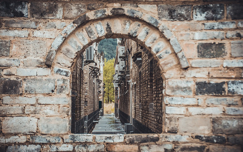 拱形摄影照片_透过砖墙的拱形窗口的古老街道建筑摄影图