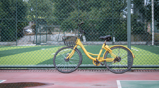 哈喽单车摄影照片_停在运动场旁的自行车