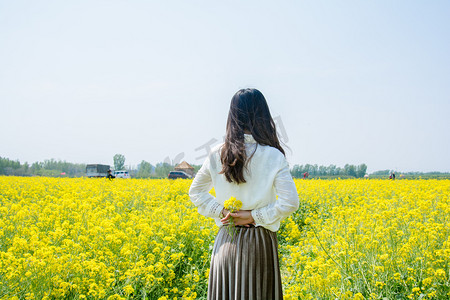 花海女孩摄影照片_女孩手拿油菜花摄影图