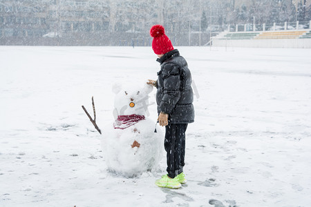 冬天的雪人摄影照片_正在堆雪人的小男孩