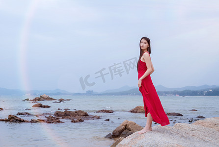 海边礁石上红衣少女摄影图