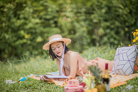 夏天户外野餐趴在地上看书的女孩