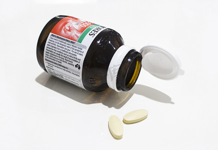 药丸药瓶摄影照片_棕色玻璃药瓶和浅色药丸摄影图