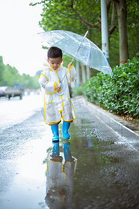 口红雨衣摄影照片_撑伞低头走路的小男孩