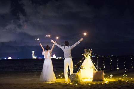国潮婚礼季摄影照片_情侣放烟花面相大海夜景拍摄