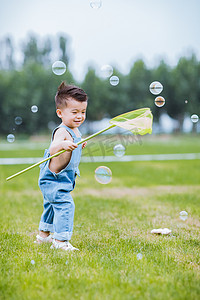 六一儿童节粉摄影照片_草地上追泡泡的小男孩