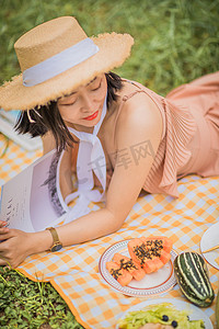 八月你好摄影照片_夏天户外野餐趴在地上看书的女孩
