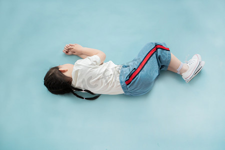 儿童睡觉摄影照片_侧躺在蓝色背景上睡觉的小女孩