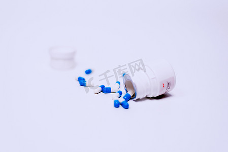复方氨酚烷胺胶囊摄影照片_倒出的药品与打开的药瓶摄影图