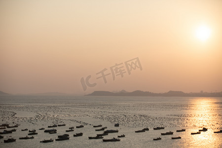 落日海边渔船停泊摄影图