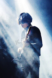吉他摄影照片_烟雾中弹吉他的男孩