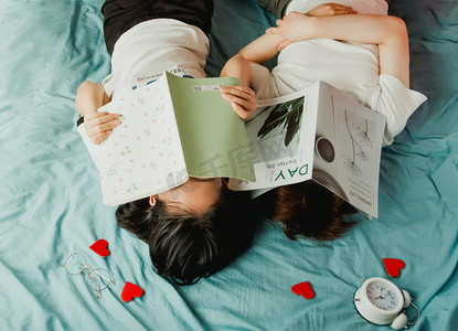 背影搂腰卡通情侣摄影照片_躺着看书的情侣摄影