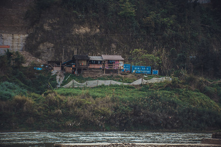 乡村河边山上的破败老房子摄影图