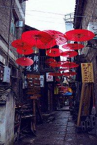 古城小巷摄影照片_在一条小巷里悬挂着的红色油纸伞摄影图