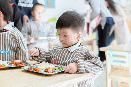 小孩摄影照片_在幼儿园吃饭的孩子