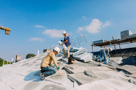 篮球场工程摄影照片_屋顶上施工的建筑工人摄影图