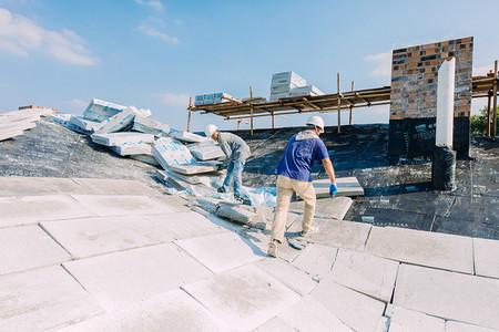 建筑摄影照片_屋顶上施工的建筑工人摄影图