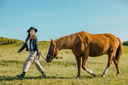 草原旅行摄影照片_在草原上牵着马美女摄影图
