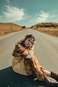 坐在草原公路上女孩摄影图