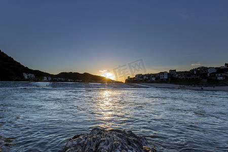 岩石水面和夕阳落日摄影图
