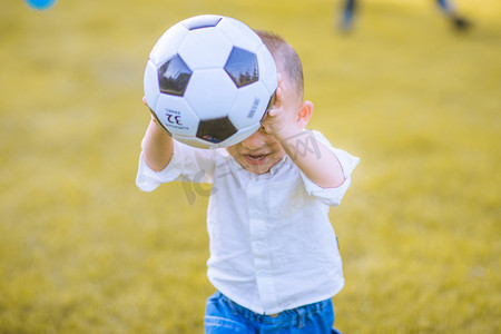 草地玩的孩子摄影照片_在草地上玩足球的小男孩