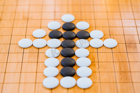 的箭头摄影照片_围棋棋盘上用黑白棋子拼成的箭头