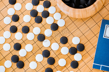 智力摄影照片_围棋棋盘上的棋子，棋罐，古书