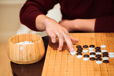 港风手持牌摄影照片_手持白棋落子下围棋