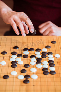 古人博弈摄影照片_手持黑棋准备落子在棋盘上