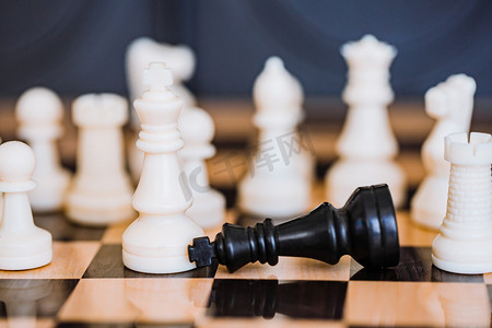 竞赛模版摄影照片_国际象棋棋盘上的白色棋子和战败的黒王