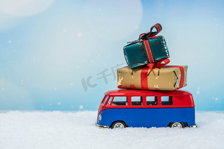 圣诞礼盒礼盒摄影照片_圣诞节雪地上拉着礼盒的汽车