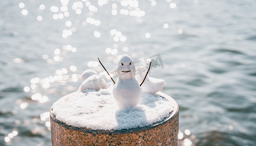 雪人摄影照片_冬天户外岸边小雪人摄影图