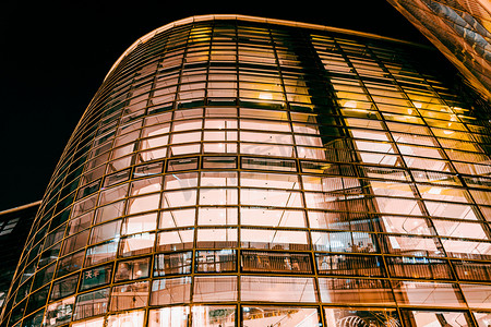 黑色炫光炫酷黄色光效摄影照片_夜景灯光下的透明玻璃高楼建筑物