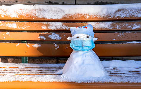 冬天公园长椅上立着的雪人摄影图
