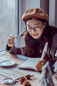 冬天文艺摄影照片_边喝咖啡边读书的女生