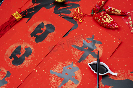 中国毛笔字摄影照片_春节在喜庆红色纸上写春联