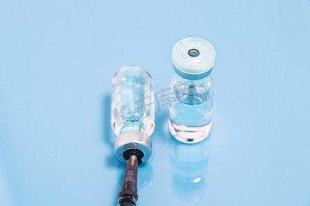疫苗蓝色摄影照片_蓝色背景前的疫情疫苗