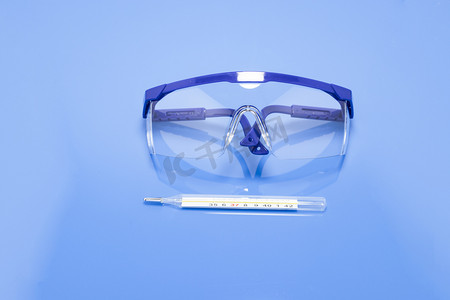 蓝色疫苗摄影照片_蓝色背景前的护目镜